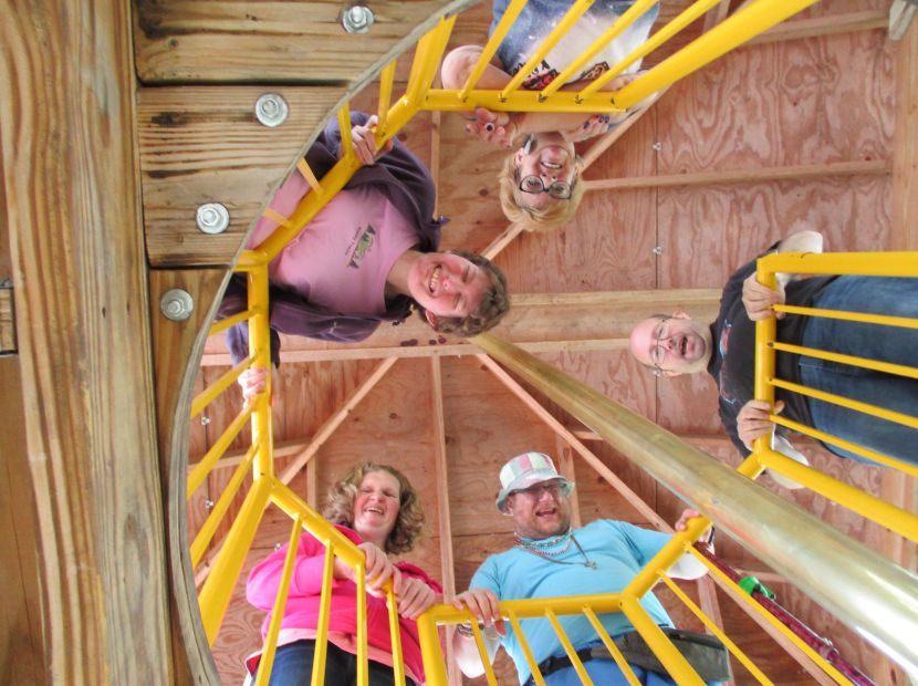 People from Skyline standing on spiral staircase looking down towards camera